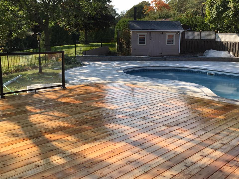 Warm-toned deck boards around a swimming pool with dark railings